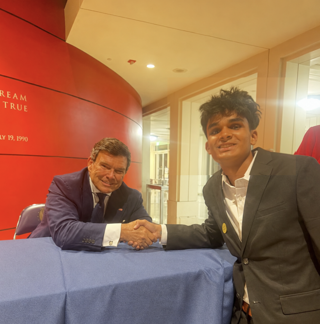 Debate Discovery Kids student shaking hands across a signing table